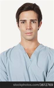 Portrait of confident young man in surgical scrubs over gray background