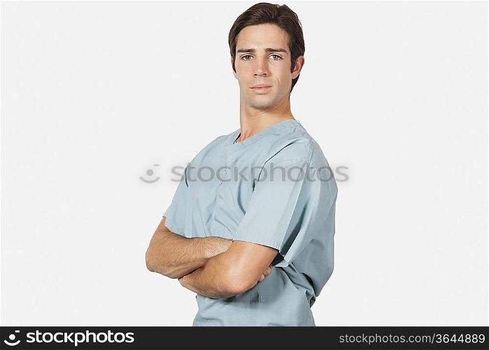 Portrait of confident young man in surgical scrubs standing against gray background