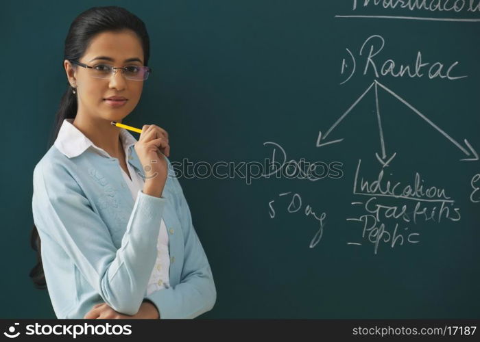 Portrait of confident young teacher against green board