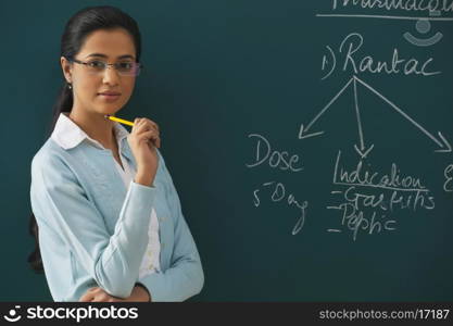 Portrait of confident young teacher against green board