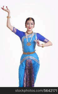 Portrait of confident young woman performing Bharatanatyam over white background