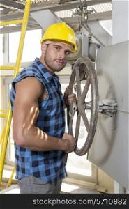 Portrait of confident young worker fixing industrial valve
