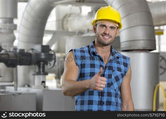 Portrait of confident young worker gesturing thumbs up in industry
