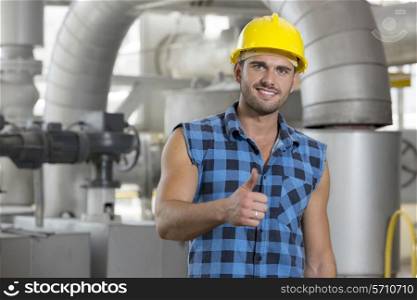 Portrait of confident young worker gesturing thumbs up in industry