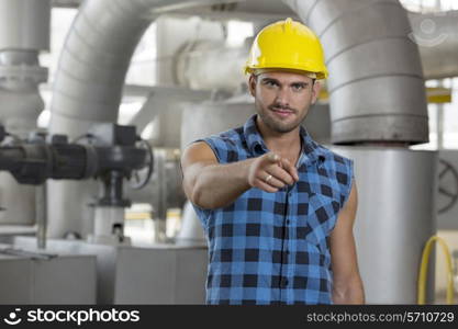 Portrait of confident young worker pointing at you in industry
