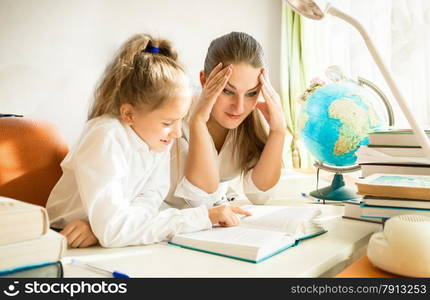 Portrait of confused mother looking at daughters complicated homework