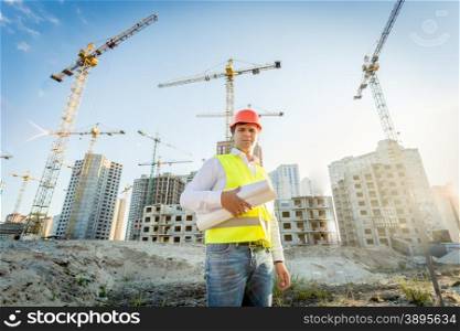 Portrait of construction inspector posing with blueprints on building site