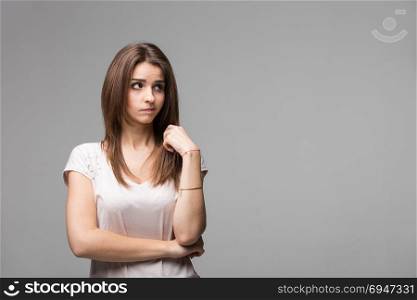 Portrait of contused thinking brunette woman. Studio shot on gray background. Portrait of contused thinking brunette woman. Studio shot on gray background.