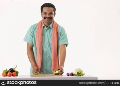 Portrait of cook servant chopping capsicum with knife in kitchen