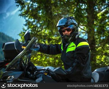 Portrait of cool biker on beautiful nature background, handsome man driving motorcycle, extreme sport, travel along Europe, joy and freedom concept