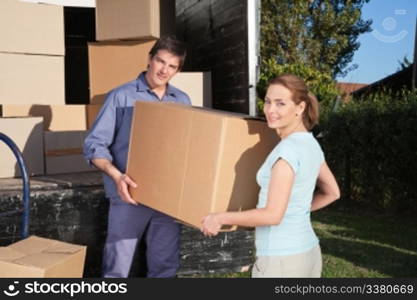 Portrait of couple carrying cardboard box while moving into new home