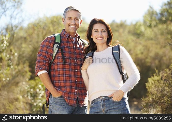 Portrait Of Couple Hiking In Countryside Wearing Backpacks