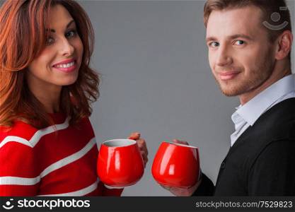 Portrait of couple holding red coffee cups, Christmas or Valentines day concept. Couple with red coffee cups
