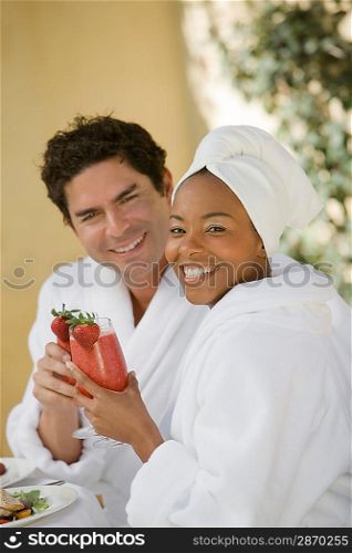 Portrait of couple in bathrobes, drinking at health spa