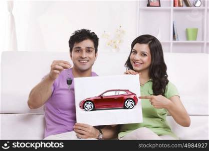 Portrait of couple pointing to picture of car
