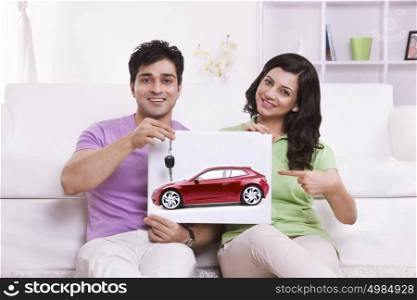 Portrait of couple pointing to picture of car
