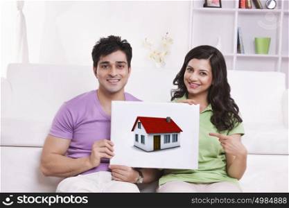 Portrait of couple pointing to picture of house