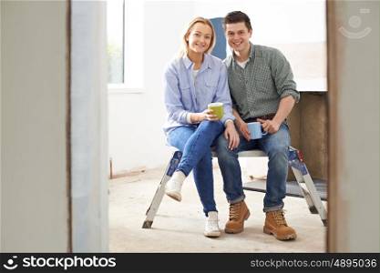 Portrait Of Couple Sitting In Property Being Rennovated