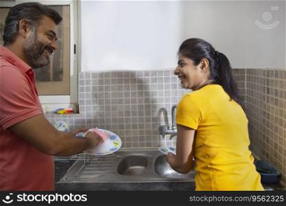 Portrait of couple washing dishes together in the kitchen