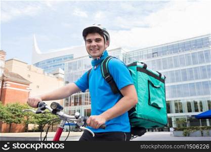 Portrait Of Courier On Bicycle Delivering Food In City