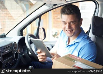 Portrait Of Courier With Digital Tablet In Van Delivering Package To  House