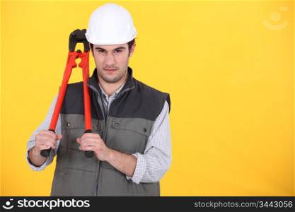 portrait of craftsman holding spanner against yellow background