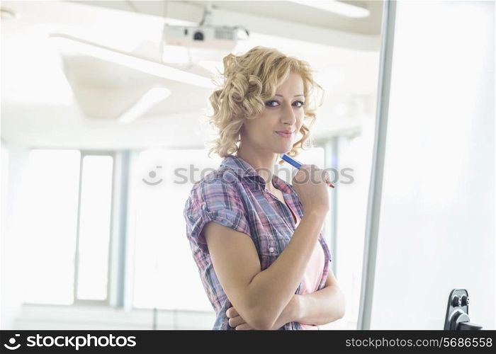 Portrait of creative businesswoman standing in front of presentation board in office