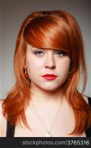 Portrait of creative redhaired girl. Young woman with cherry fruit earing on gray. Studio shot. Fashion and accessories.