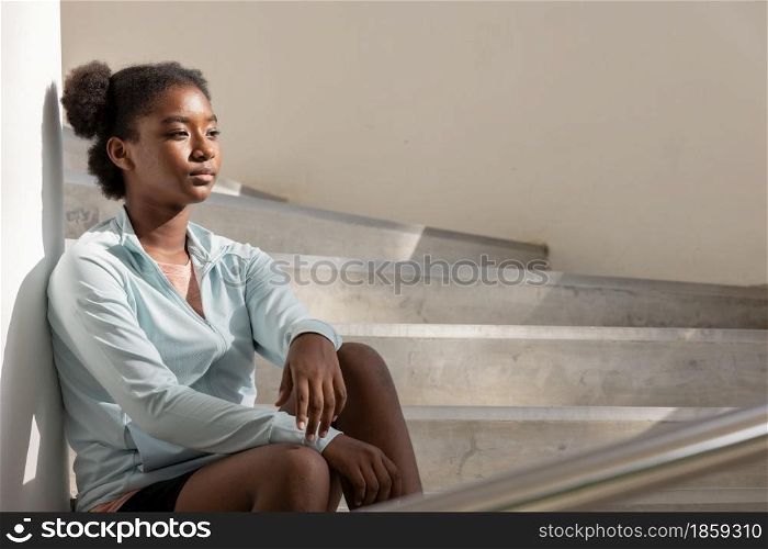 Portrait of curly hair woman sitting on steps and staircases and looking away.