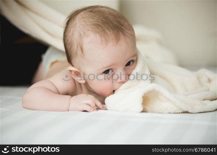 Portrait of cute 6 months baby lying on white sheets