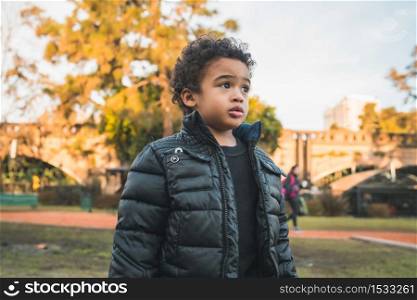 Portrait of cute african american little boy standing outdoors in the park.