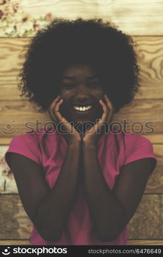 portrait of cute african american woman with afro hairstyle while posing against old retro wooden background. portrait of afro american woman