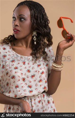 Portrait of cute african woman posing - holding sunglasses and looking away