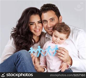 Portrait of cute arabic family sitting in the studio and holding in hands blue men-shape bonding paper, connection of people concept