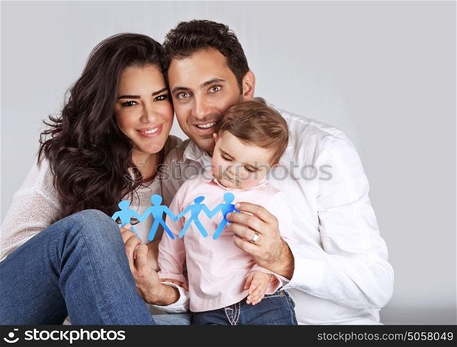 Portrait of cute arabic family sitting in the studio and holding in hands blue men-shape bonding paper, people unity concept
