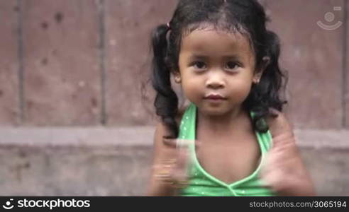 Portrait of cute Asian female child smiling at camera and clapping hands