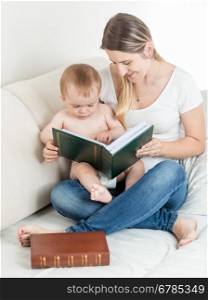 Portrait of cute baby boy and mother looking at photos in family album