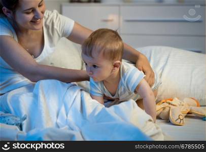 Portrait of cute baby boy crawling on bed at night