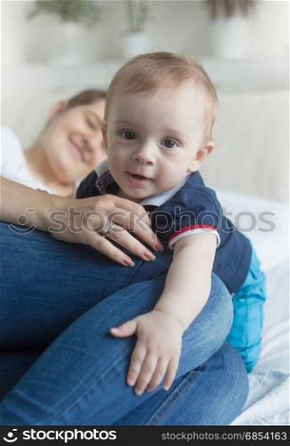 Portrait of cute baby boy crawling on bed over mother