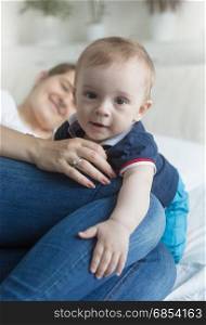 Portrait of cute baby boy crawling on bed over mother