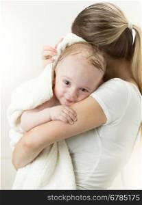 Portrait of cute baby boy hugging mother after having bath