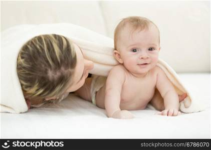 Portrait of cute baby boy lying on bed mother