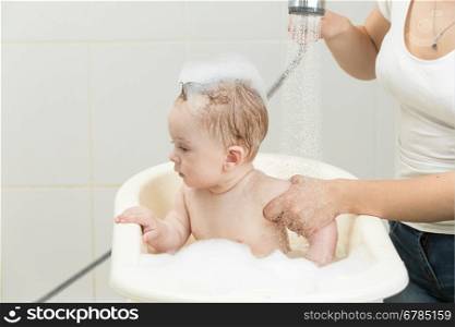 Portrait of cute baby boy sitting in bath full of foam