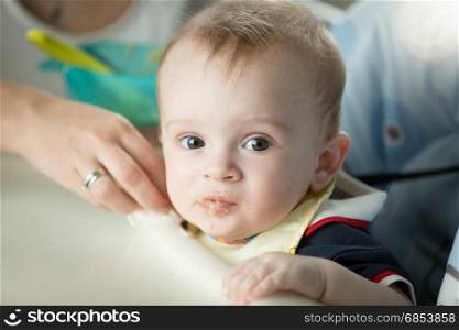 Portrait of cute baby boy sitting in highchair and looking at camera