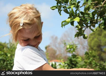 Portrait of cute baby girl posing near leafage