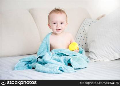 Portrait of cute baby sitting on bed after having bath