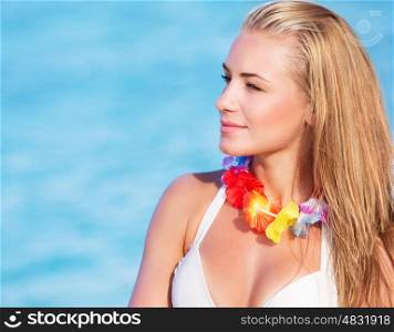 Portrait of cute blond female wearing beautiful Hawaiian leis, having fun on the beach, tropical party with traditional flowers garland on neck&#xA;