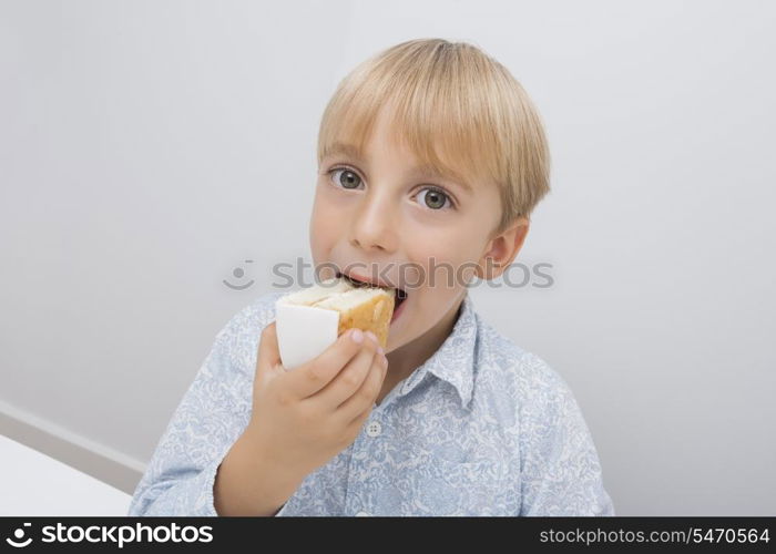 Portrait of cute boy eating cake slice in house