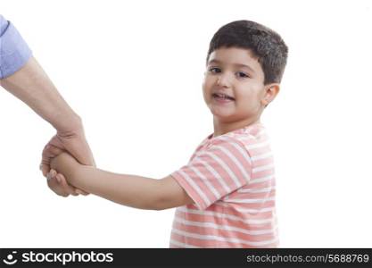 Portrait of cute boy holding father&rsquo;s hand against white background