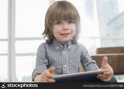 Portrait of cute boy holding tablet computer at home